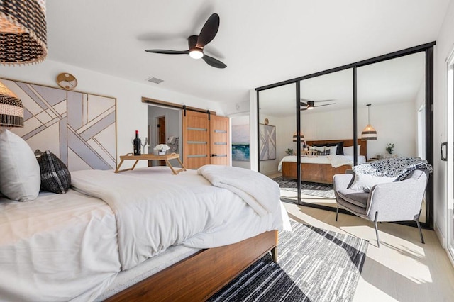 bedroom featuring ceiling fan, a barn door, and a closet