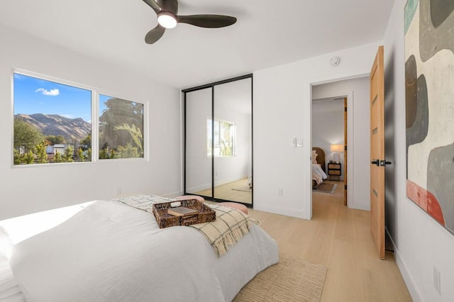 bedroom featuring a mountain view, light hardwood / wood-style flooring, a closet, and ceiling fan