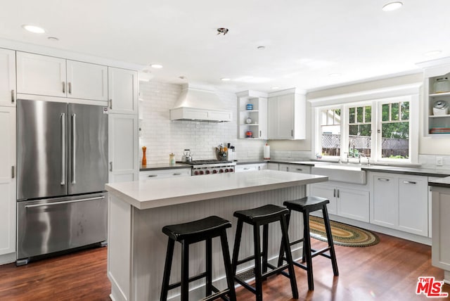 kitchen featuring white cabinets, a kitchen island, custom range hood, and high end fridge