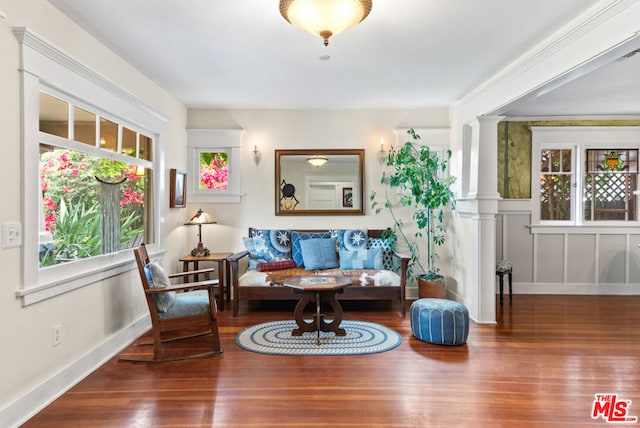 living area featuring wood-type flooring, breakfast area, a wealth of natural light, and decorative columns