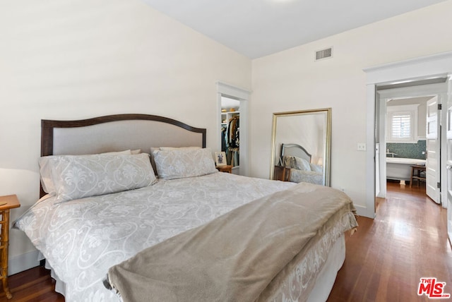 bedroom with a walk in closet, a closet, and dark hardwood / wood-style floors