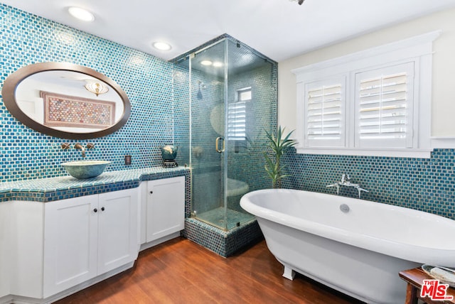 bathroom featuring vanity, wood-type flooring, backsplash, and shower with separate bathtub