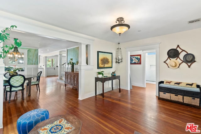 interior space with ornate columns, dark hardwood / wood-style flooring, and a notable chandelier