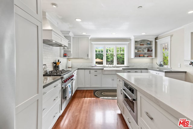 kitchen with appliances with stainless steel finishes, white cabinetry, decorative backsplash, dark hardwood / wood-style floors, and ornamental molding