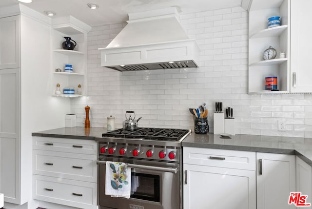 kitchen featuring decorative backsplash, custom exhaust hood, white cabinets, and premium range