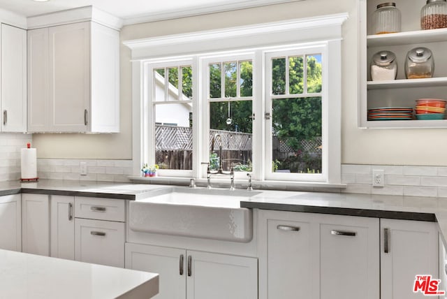 kitchen featuring a wealth of natural light, white cabinets, backsplash, and sink