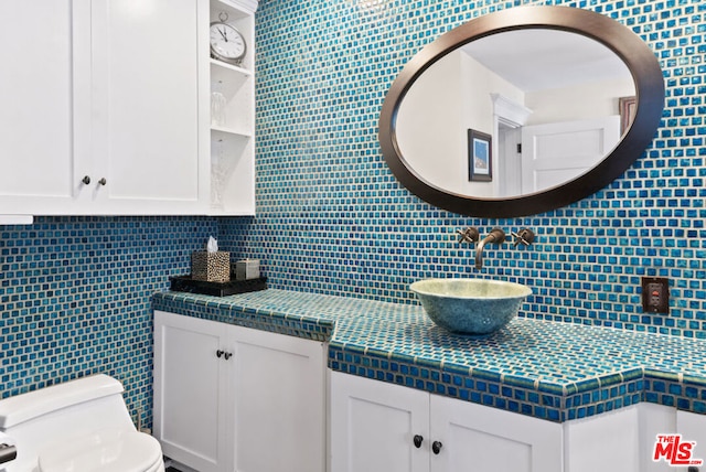 bathroom featuring toilet, vanity, and tasteful backsplash