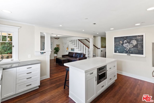 kitchen featuring oven, a center island, a breakfast bar, white cabinets, and dark hardwood / wood-style flooring