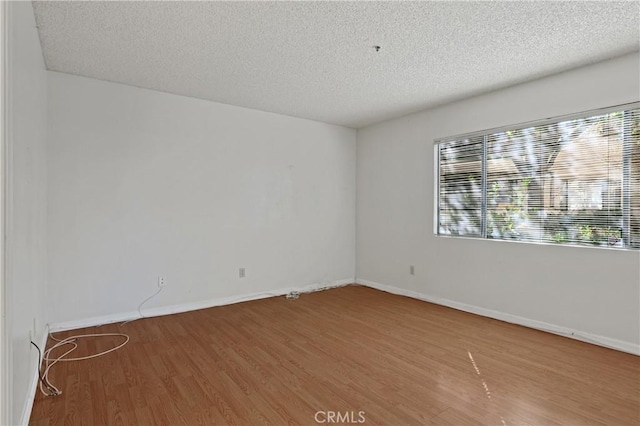 empty room featuring a textured ceiling and hardwood / wood-style flooring