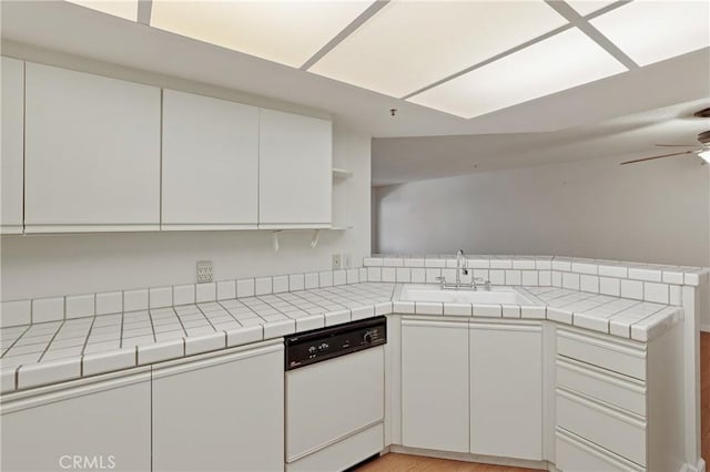 kitchen with white dishwasher, sink, white cabinetry, and tile counters