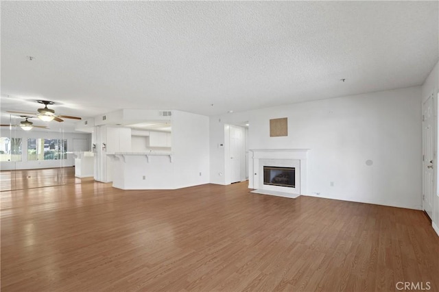 unfurnished living room with a textured ceiling, ceiling fan, and hardwood / wood-style floors