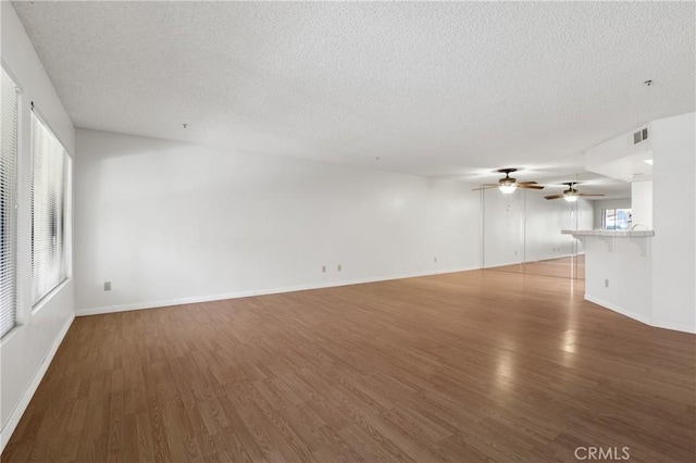 unfurnished living room with a textured ceiling and dark hardwood / wood-style floors