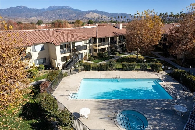 view of swimming pool featuring a mountain view, a community hot tub, and a patio area