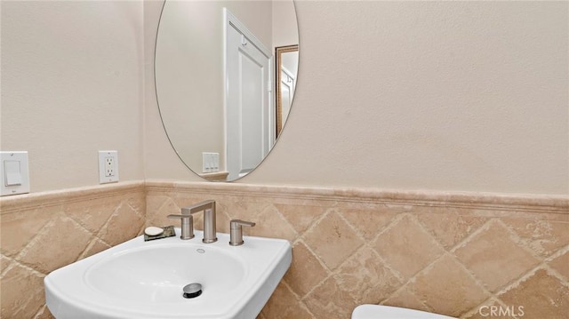 bathroom featuring tile walls and sink