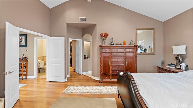 bedroom featuring hardwood / wood-style flooring, ensuite bathroom, and vaulted ceiling with beams