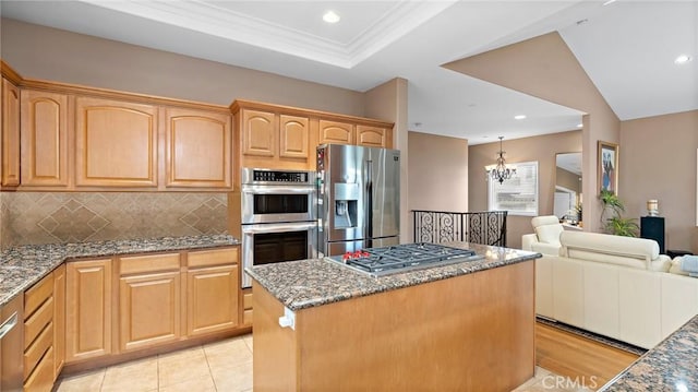 kitchen featuring tasteful backsplash, a notable chandelier, a kitchen island, stainless steel appliances, and dark stone counters