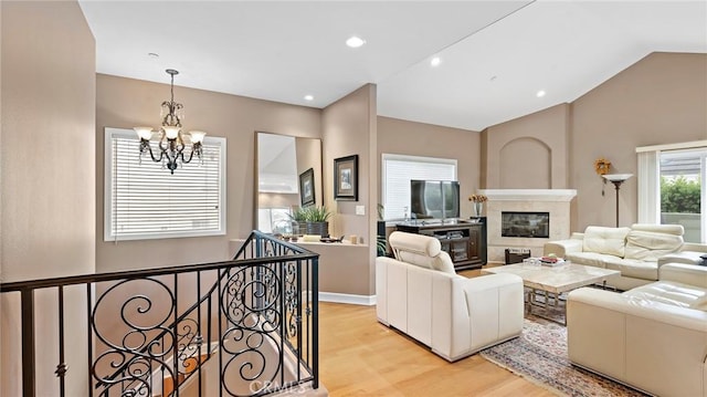 living room with lofted ceiling, light hardwood / wood-style flooring, and a notable chandelier