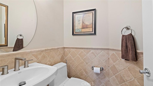 bathroom with sink, tile walls, and toilet