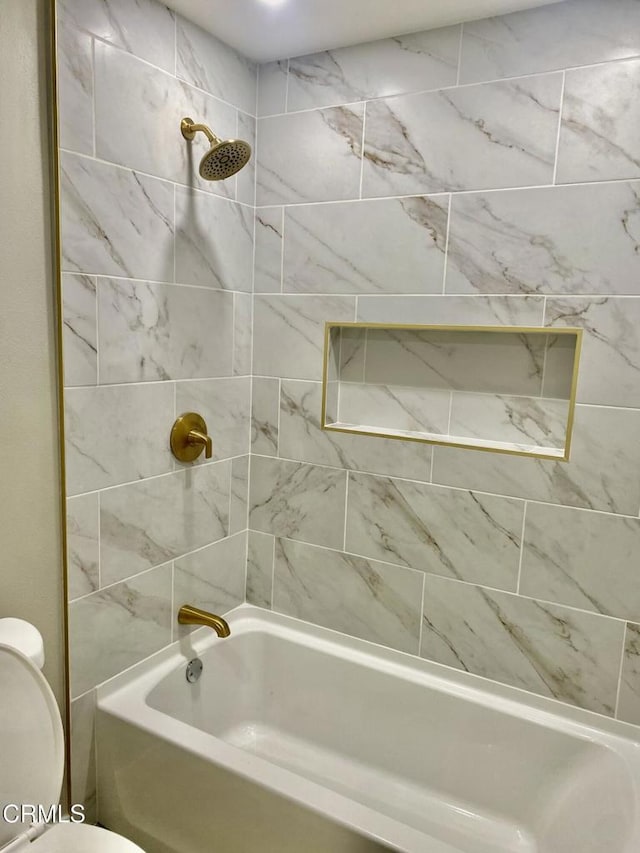 bathroom featuring tiled shower / bath combo and toilet