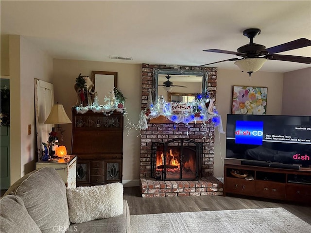 living room with ceiling fan, a brick fireplace, and hardwood / wood-style flooring