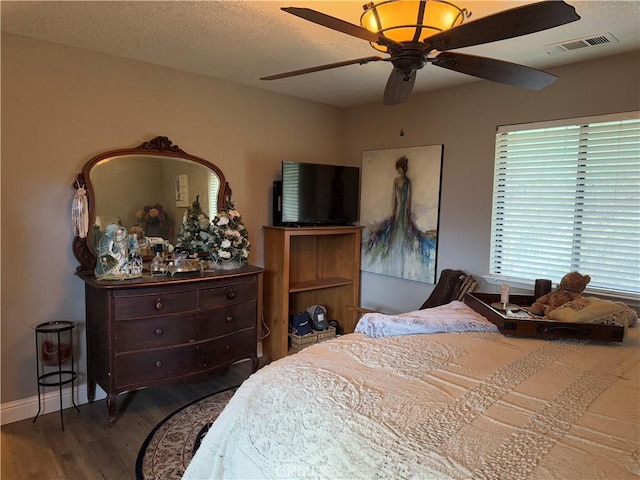 bedroom with ceiling fan, a textured ceiling, and dark hardwood / wood-style floors