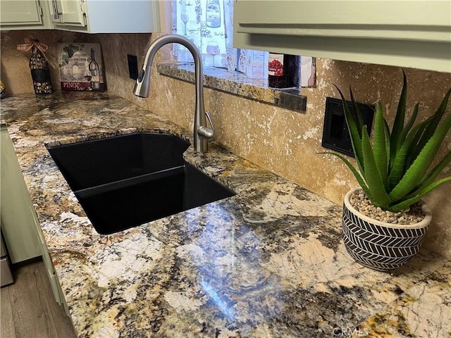 interior details featuring backsplash, sink, and stone counters