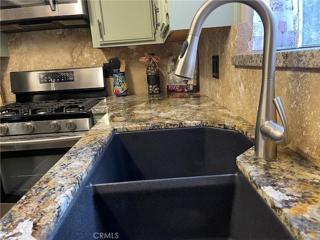 kitchen featuring stone countertops, backsplash, green cabinets, and stainless steel gas range