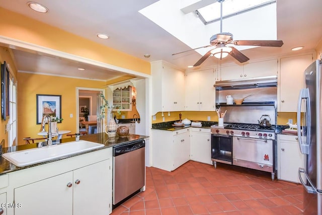 kitchen with sink, light tile patterned floors, a skylight, stainless steel appliances, and white cabinets