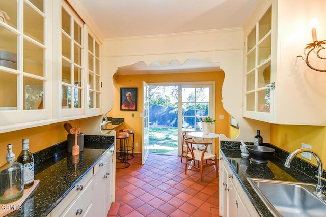 kitchen with ornamental molding, sink, light tile patterned floors, and white cabinets