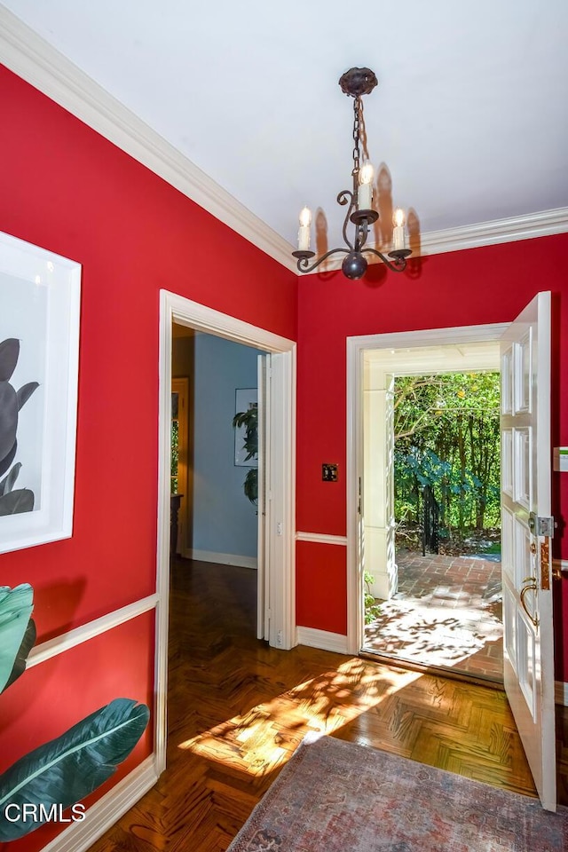 entryway with a notable chandelier, ornamental molding, and dark parquet floors