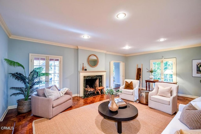 living room featuring a wealth of natural light, parquet flooring, ornamental molding, and a high end fireplace