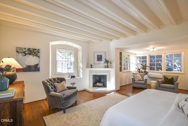 bedroom with multiple windows, dark wood-type flooring, and beam ceiling