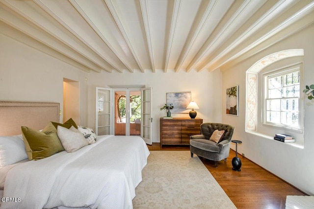 bedroom with multiple windows, hardwood / wood-style flooring, french doors, and beamed ceiling