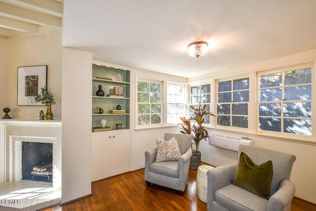 living area featuring a brick fireplace, a wall mounted air conditioner, and dark hardwood / wood-style floors