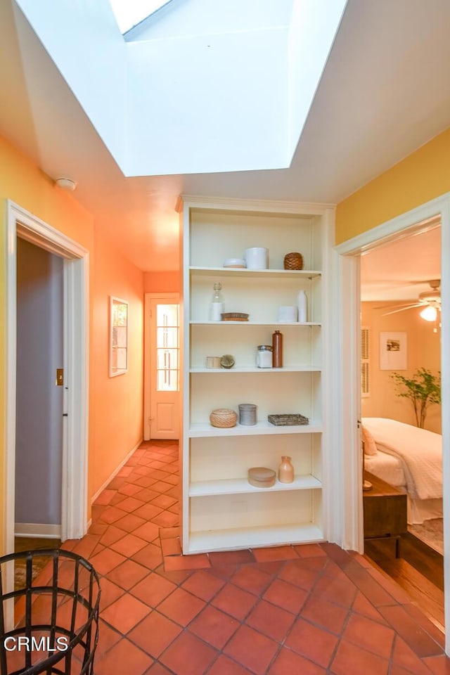 corridor featuring a skylight and tile patterned floors