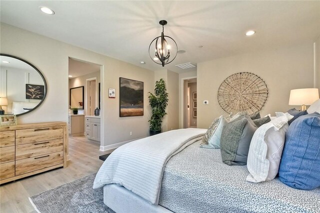 bedroom with ensuite bathroom, an inviting chandelier, and light wood-type flooring