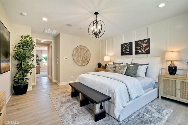 bedroom with light wood-type flooring and an inviting chandelier