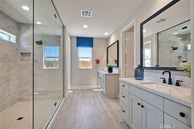 bathroom featuring hardwood / wood-style flooring, plenty of natural light, and tiled shower