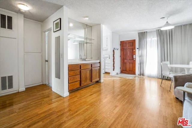 living room featuring a textured ceiling, light hardwood / wood-style floors, and sink