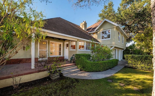 view of front of house with covered porch, a front lawn, and a garage