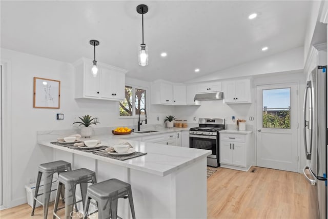 kitchen with lofted ceiling, kitchen peninsula, sink, stainless steel appliances, and white cabinets