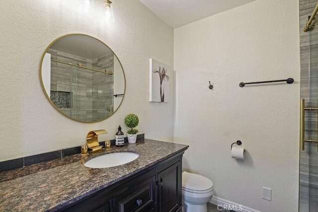 bathroom with toilet, vanity, and a shower with door