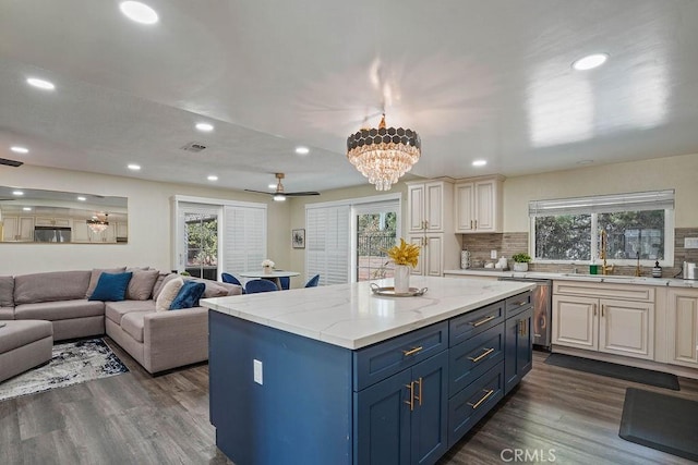 kitchen featuring white cabinetry, tasteful backsplash, light stone countertops, a kitchen island, and sink