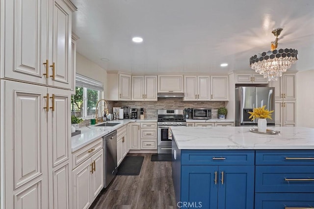 kitchen featuring a kitchen island, sink, light stone countertops, stainless steel appliances, and a chandelier