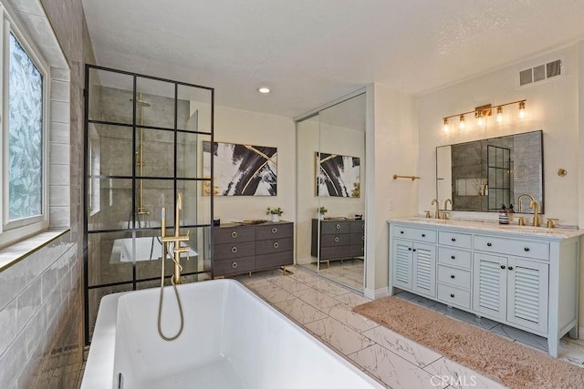 bathroom with a tub, a wealth of natural light, vanity, and a textured ceiling