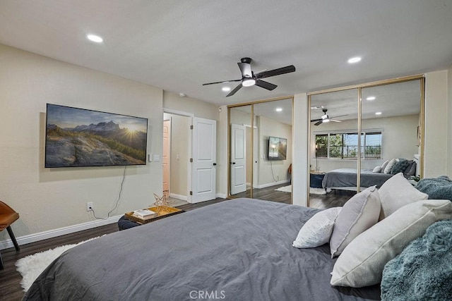 bedroom featuring ceiling fan, dark hardwood / wood-style flooring, and two closets