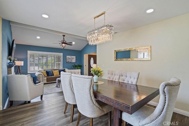 dining space featuring lofted ceiling, ceiling fan with notable chandelier, and hardwood / wood-style flooring