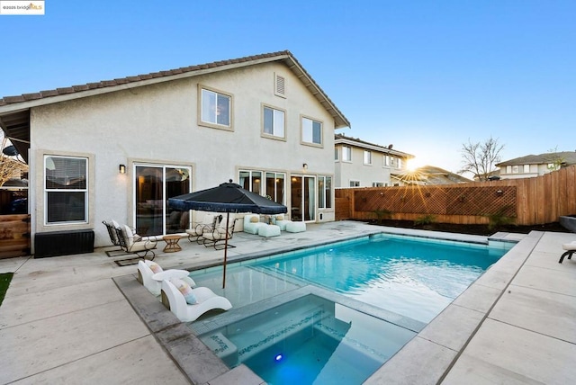 back of house featuring a swimming pool with hot tub and a patio area