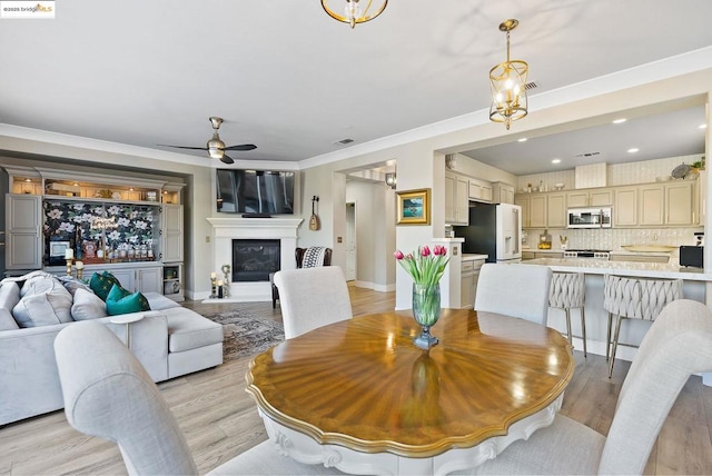 dining room featuring ceiling fan with notable chandelier, light hardwood / wood-style flooring, and crown molding