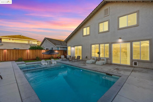 pool at dusk featuring a patio